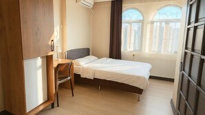 Una camera d'albergo moderna con letto, scrivania e armadio.