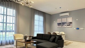 Una sala moderna con un sofá modular, una mesita y un comedor al fondo.
