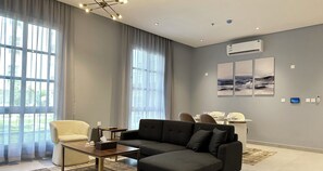 Un salon moderne avec un canapé d’angle, une petite table et un coin repas à l’arrière-plan.