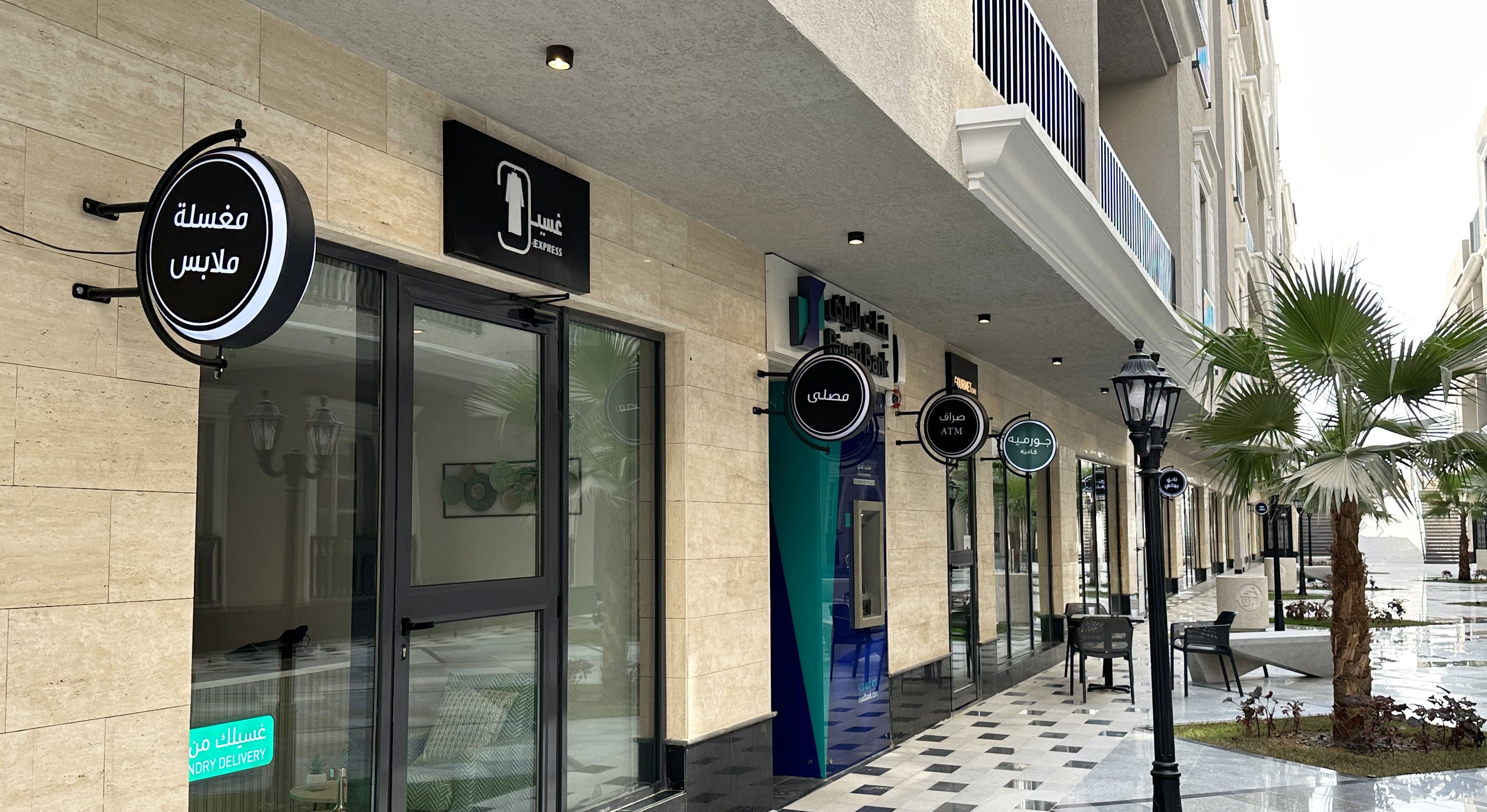 Un immeuble commercial doté d’une vitrine, d’une enseigne indiquant un service de blanchisserie et d’un distributeur automatique de billets.