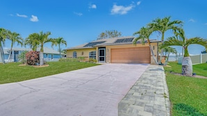 A residential house with a garage, a paved driveway, and palm trees. - Cape Coral Home w/ Screened Porch: 4 Mi to Beach! (Cape Coral)