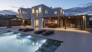 A modern two-story house with a pool, outdoor seating, and a pergola.