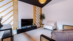 Una sala de estar moderna con un mueble de entretenimiento negro, un sofá blanco y una silla de ratán.