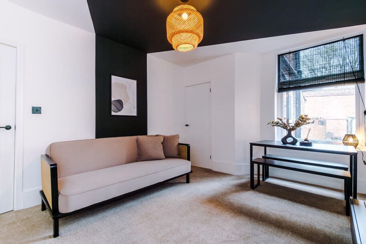 Una sala moderna con un sofá color beige, una mesa de centro negra y un colgante de luz.