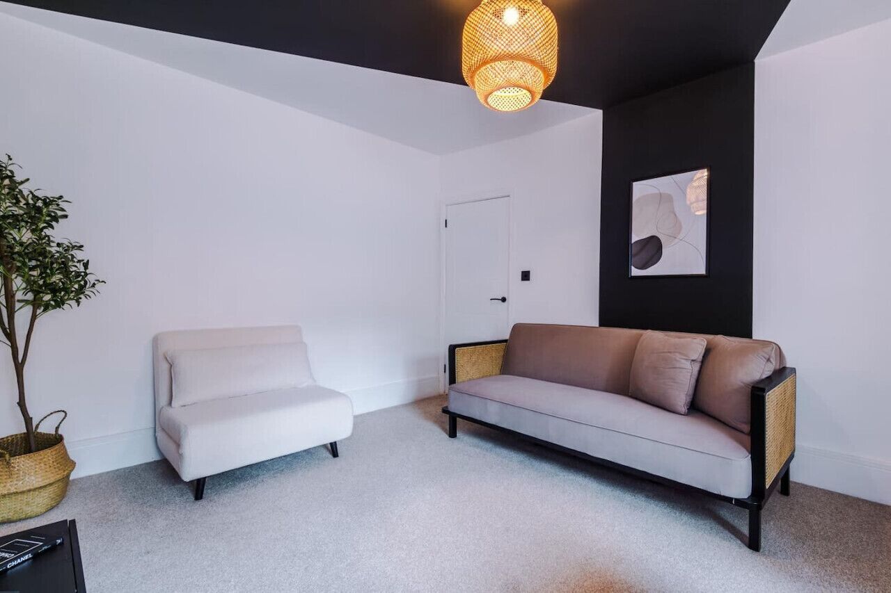 Un salon moderne avec un canapé blanc, un canapé marron, une plante en pot et un luminaire suspendu.