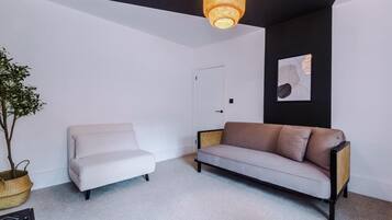 Un salon moderne avec un canapé blanc, un canapé marron, une plante en pot et un luminaire suspendu.