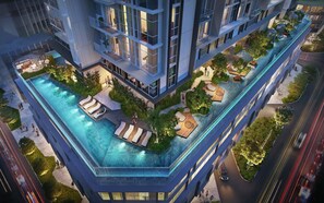 A modern high-rise building with a rooftop infinity pool, outdoor seating, and lush landscaping. - Kotrip Metropole Paradise Vacation (Ho Chi Minh City)