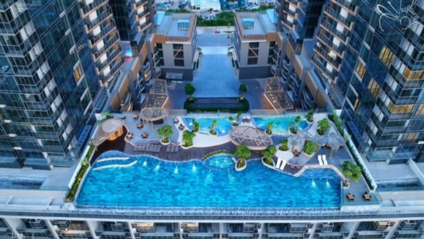 Ein Hochhaus-Hotel mit einem zentral gelegenen Schwimmbad, mehreren Balkonen und einer angelegten Terrassenanlage.