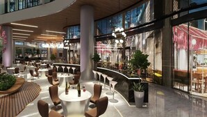 Eine geräumige Lobby mit modernen Sitzgelegenheiten, einem zentralen Barbereich und großen Fenstern mit Blick ins Freie.
