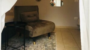 Ein Schlafzimmer mit Bett, Nachttisch, Spiegel und einer wandmontierten Leuchte in Sonnenform.