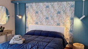 A bedroom with a large bed, a wooden ceiling, a patterned wall, and a small wooden stool. - Wonderful cottage with swimming pool 100 mt from the sea 🌊 (Trabia)