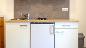 A compact kitchen with a sink, a stove, and a dishwasher. - Alpen-hostel - Apartment Mittagsonne - Buxacher Straße 23 mit Motoradvermietung (Memmingen)