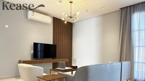 A modern living room with a sofa, a TV, a small table, and a ceiling light fixture.
