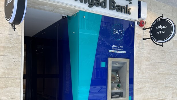 The exterior of a Riyad Bank branch with a 24/7 ATM and a cash withdrawal service.