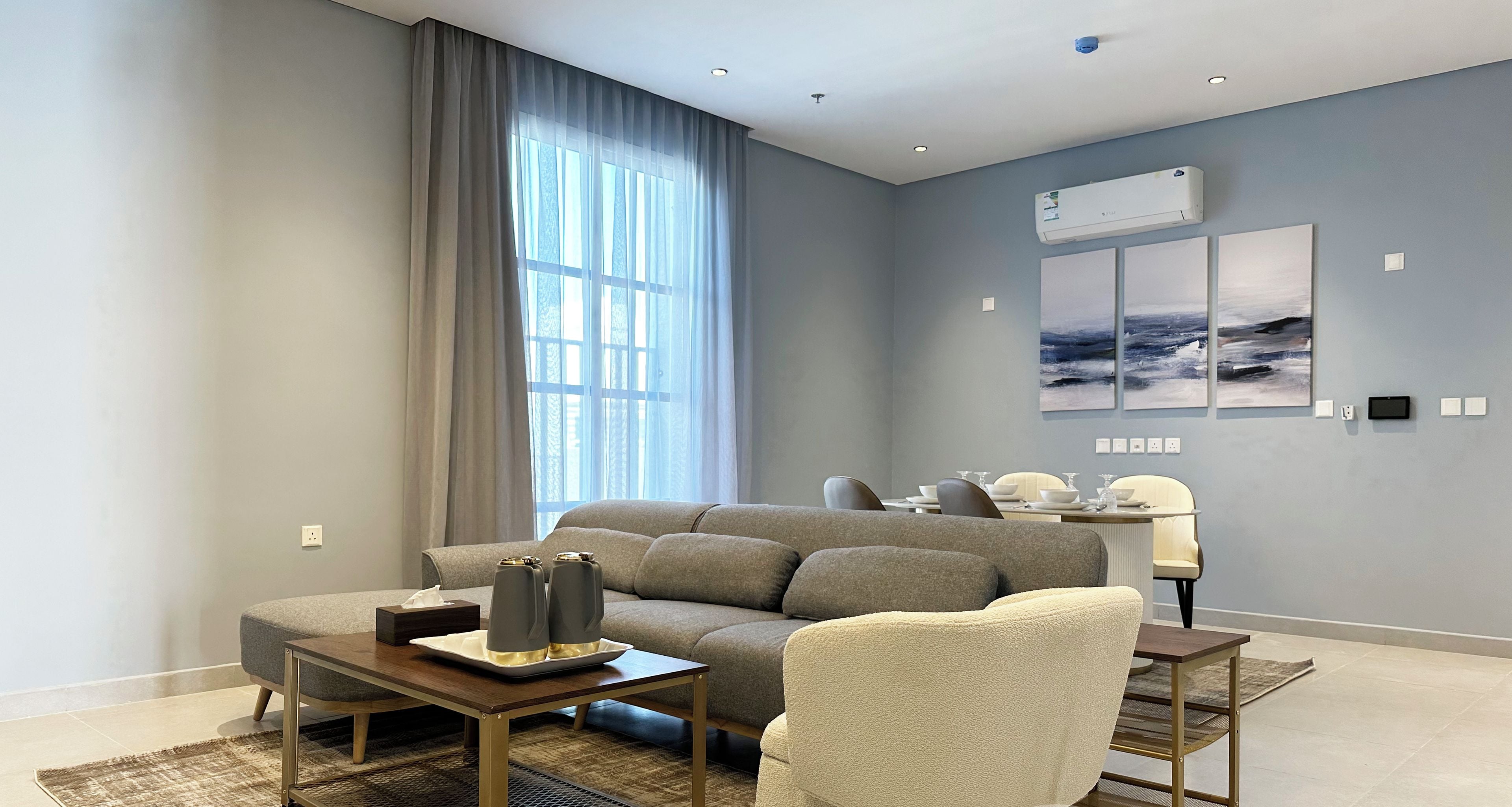 Una sala moderna con sofá, sillón, mesa de centro y comedor con lámpara y mesa.