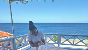 Une séance de massage en plein air, sur un balcon offrant une vue sur l’océan.