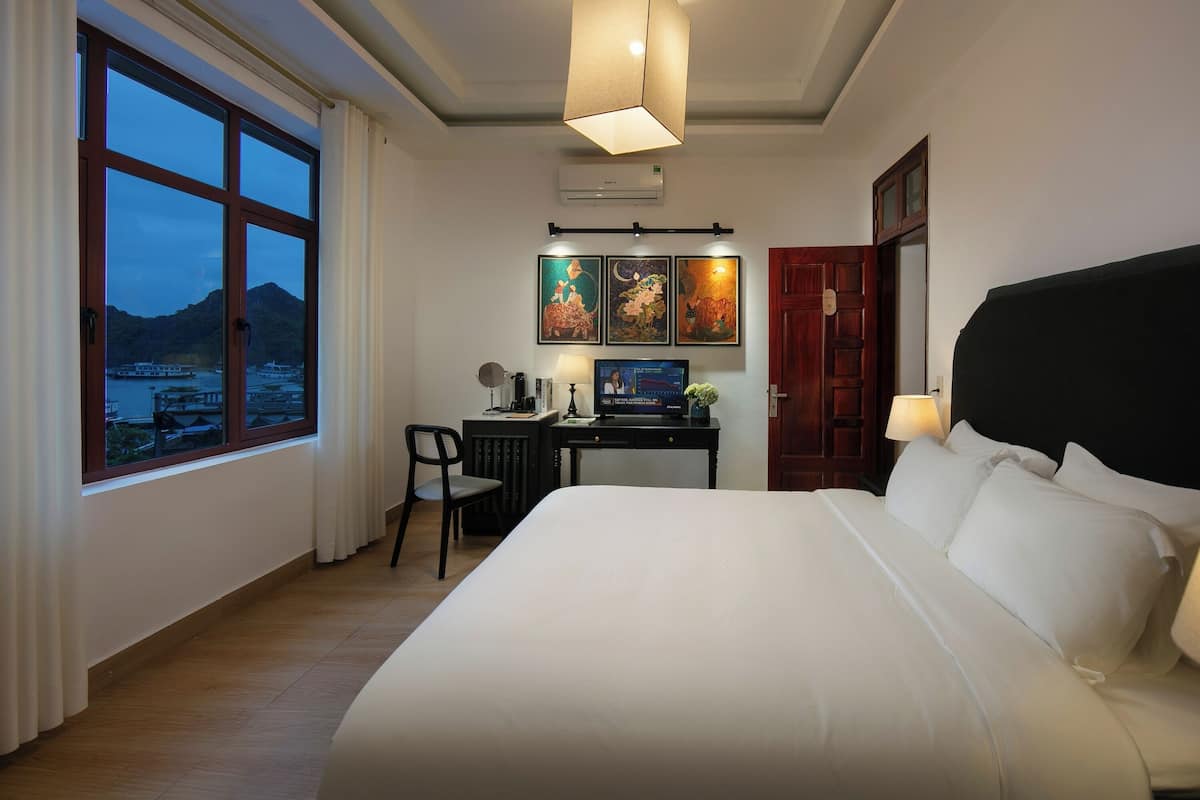 Een hotelkamer met een groot bed, een bureau met stoel, een televisie en kunst aan de muur.