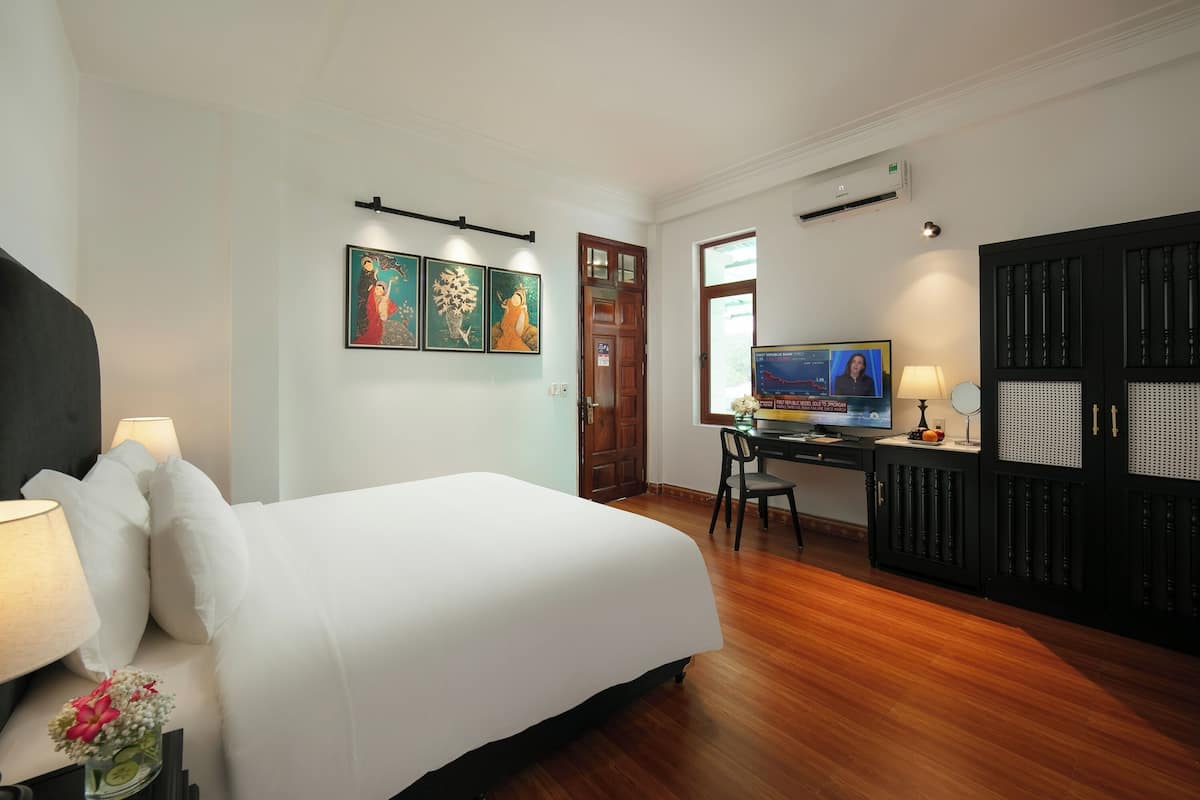 Een hotelkamer met een bed, een bureau, een televisie en kunst aan de muur.