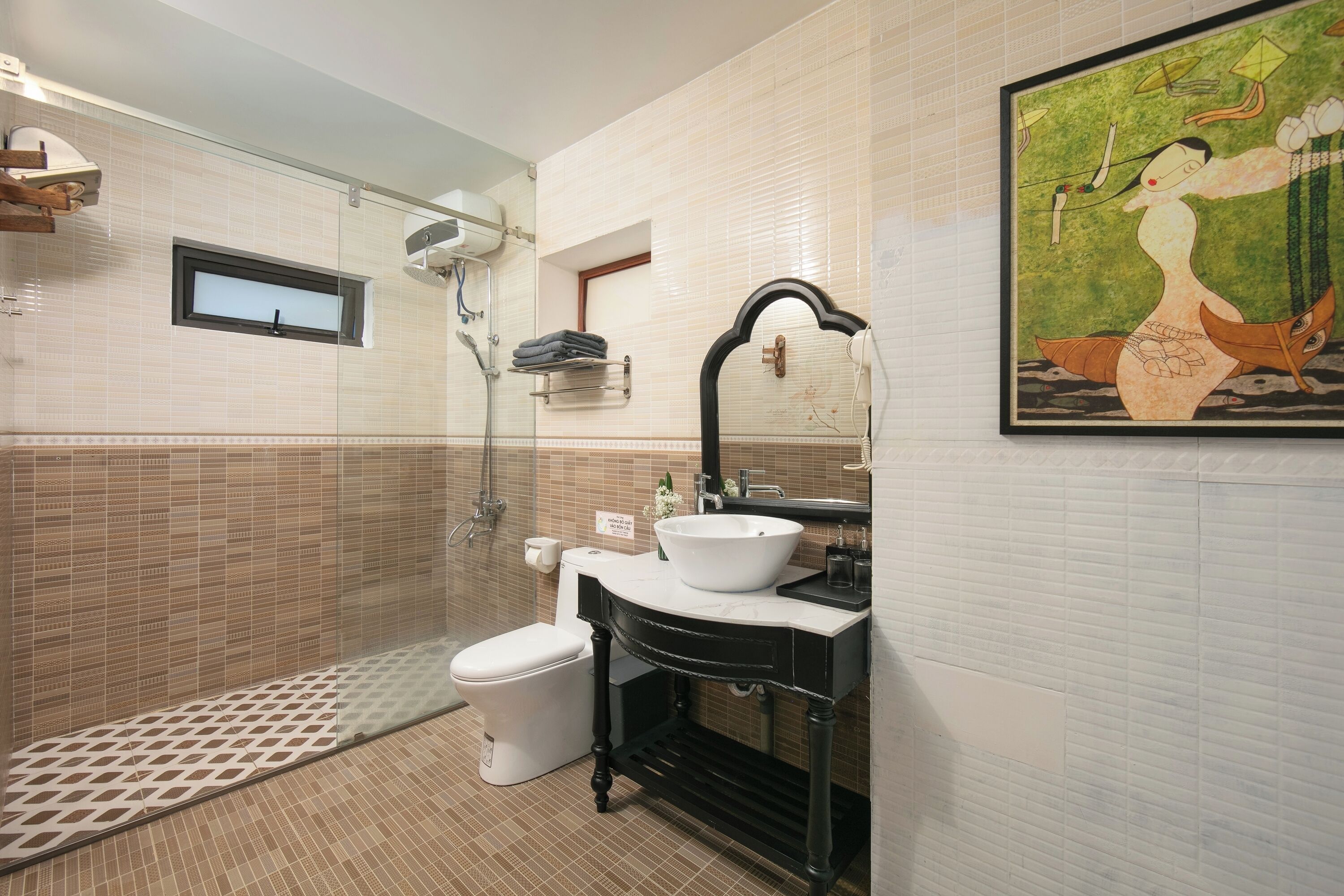 A bathroom with a white sink, black vanity, and a glass shower enclosure.
