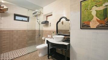 A bathroom with a white sink, black vanity, and a glass shower enclosure.