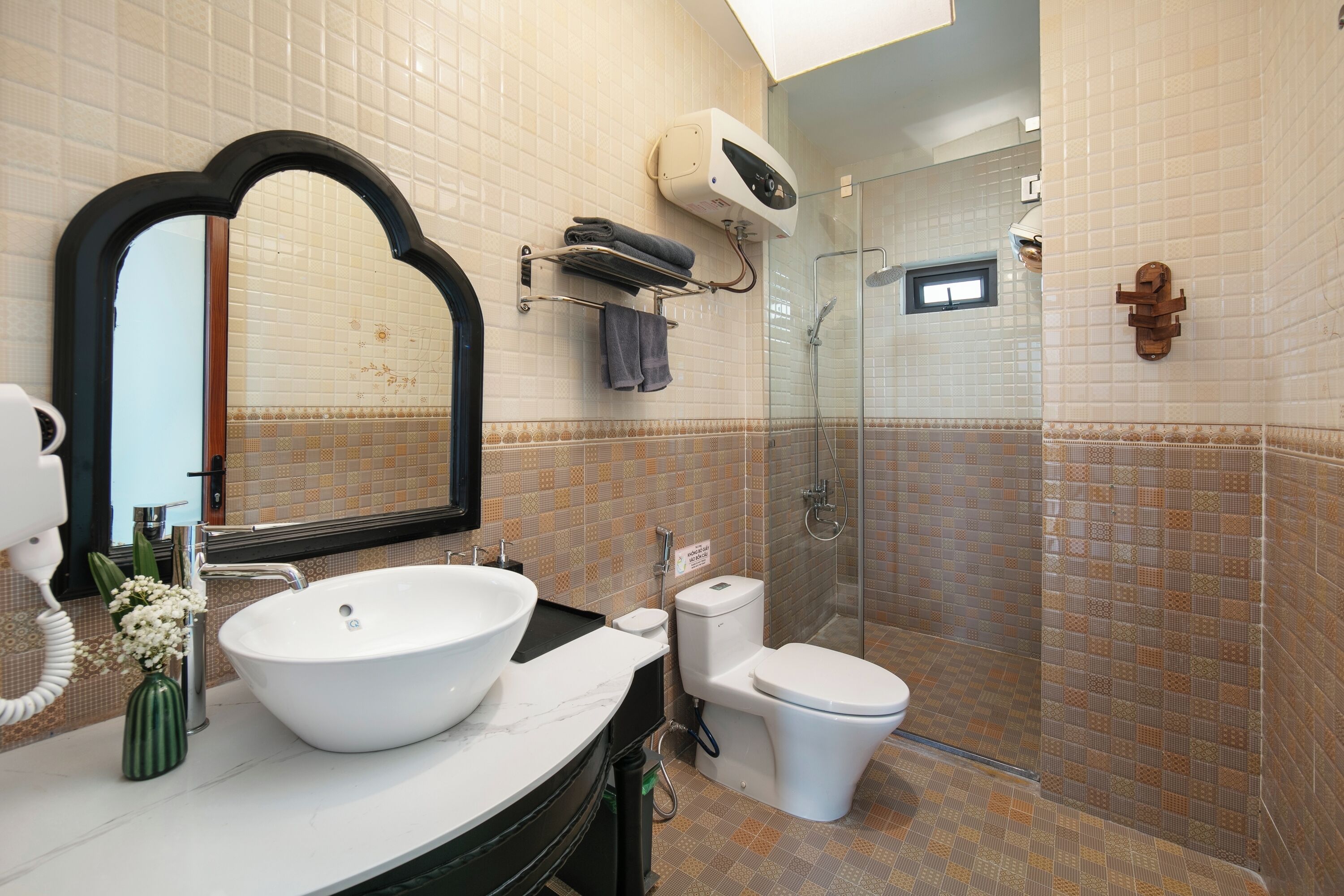 A bathroom with a large mirror, a sink, a toilet, and a shower area.