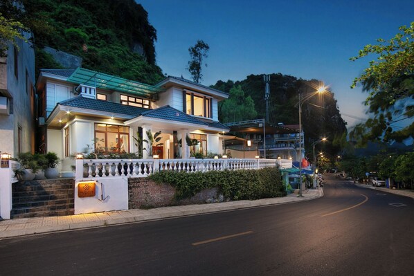 Uma casa moderna de dois andares, com varanda, entrada bem iluminada e acesso pavimentado.