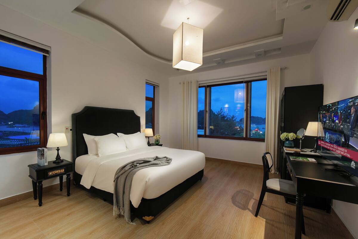 Een hotelkamer met een groot bed, een bureau met een computer en een televisie.
