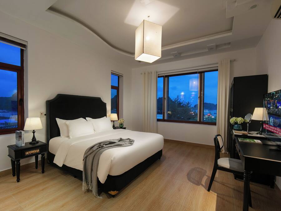 Una habitación de hotel con una cama grande, un escritorio con una computadora y un televisor.