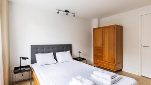 Une chambre d’hôtel comprenant un lit, une armoire, une table de chevet et une petite table.