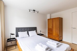A hotel room with a bed, a wardrobe, a bedside table, and a nightstand.
