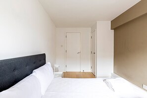 Una habitación de hotel con una cama, una mesita y una puerta.