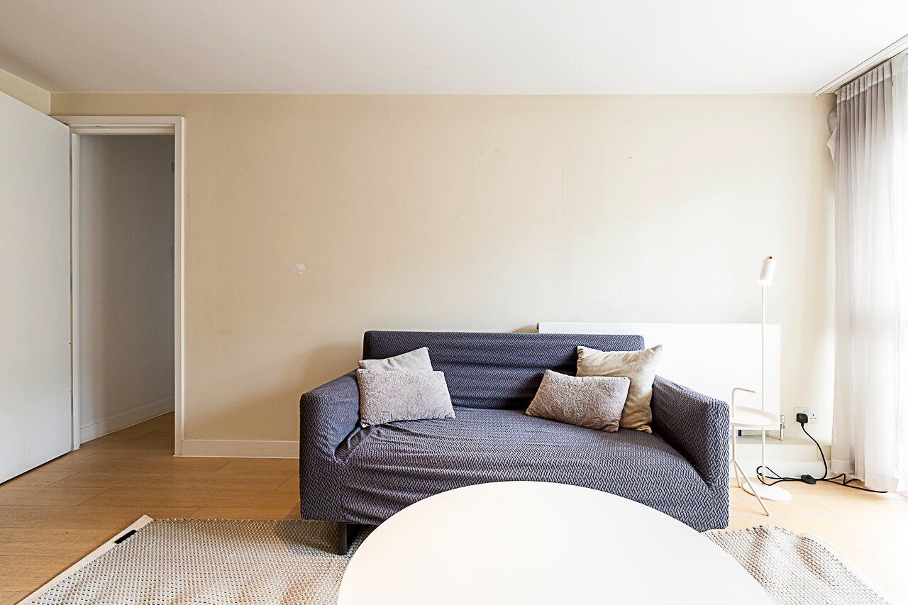 A modern living room with a dark blue sofa, two pillows, a white coffee table, and a floor lamp.