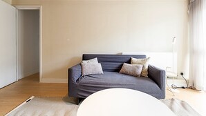 Un salon moderne avec un canapé bleu foncé, deux coussins, une table basse blanche et un lampadaire.