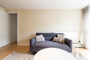 A modern living room with a dark blue sofa, two pillows, a white coffee table, and a floor lamp.