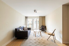 Un salon comprenant un canapé, un fauteuil, une petite table et un chevalet.