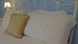 A neatly made bed with white linens and a decorative pillow. - Country Hideaways | Cobblestone Cottage | Ripon (Ripon)