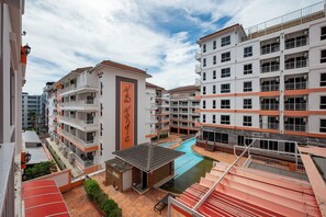 Un hotel de varios pisos con balcones, piscina y terraza en la azotea.
