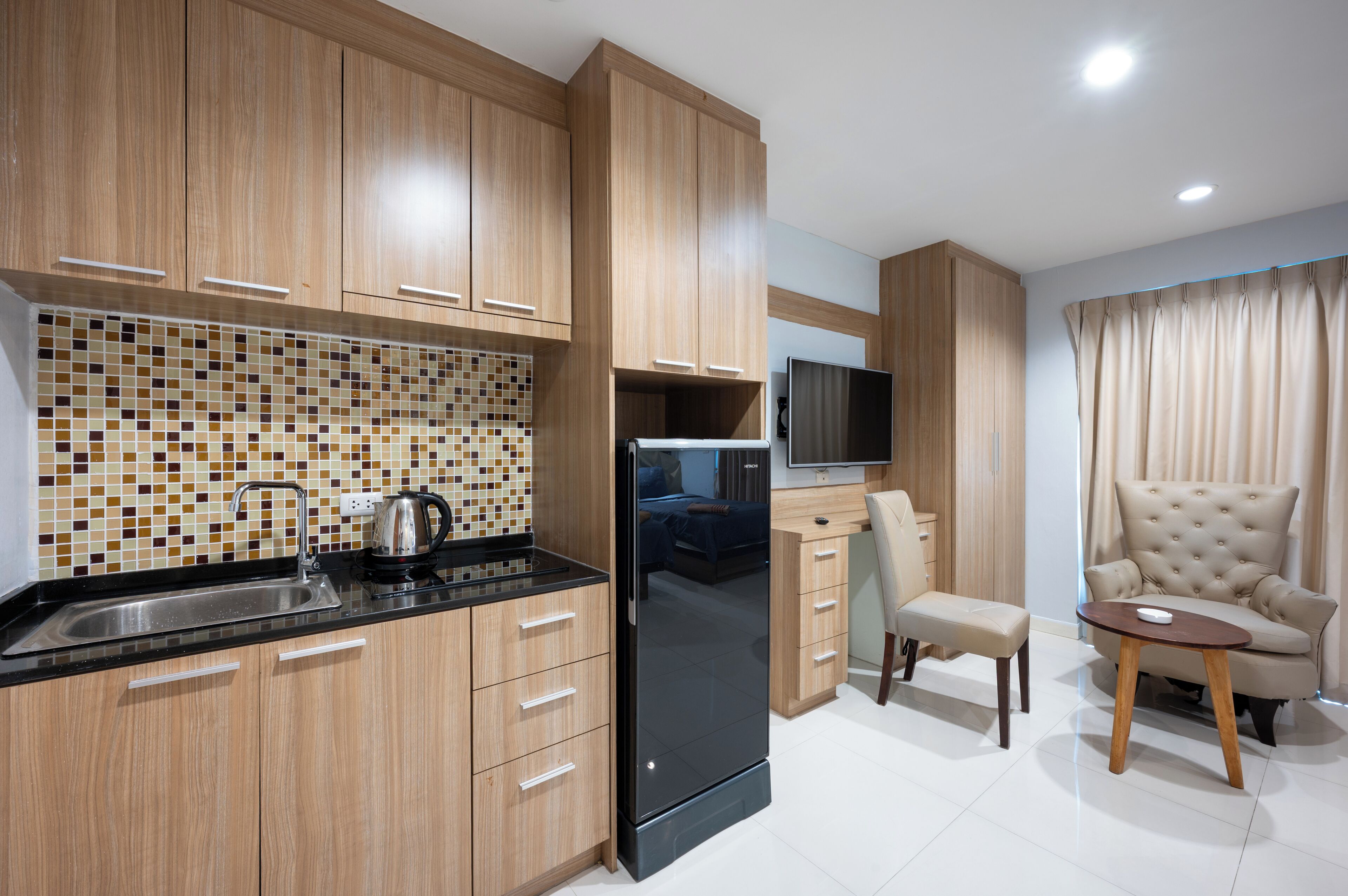 A modern kitchen with wooden cabinets, a black refrigerator, and a tiled backsplash.