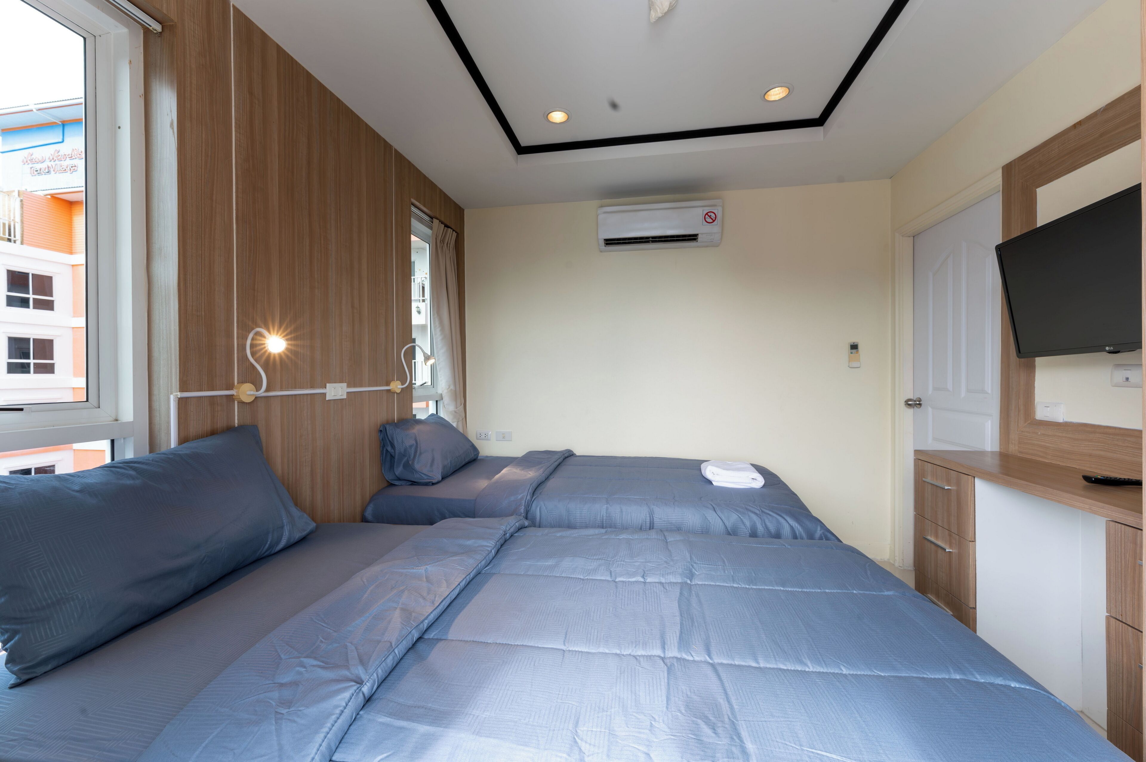 Ein Schlafzimmer mit zwei Betten, einem Fernseher und einer Klimaanlage.