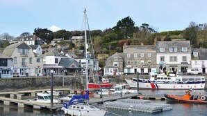 A harbor with boats, a pier, and buildings with various signs. - 1 bedroom accommodation in Padstow (Padstow)