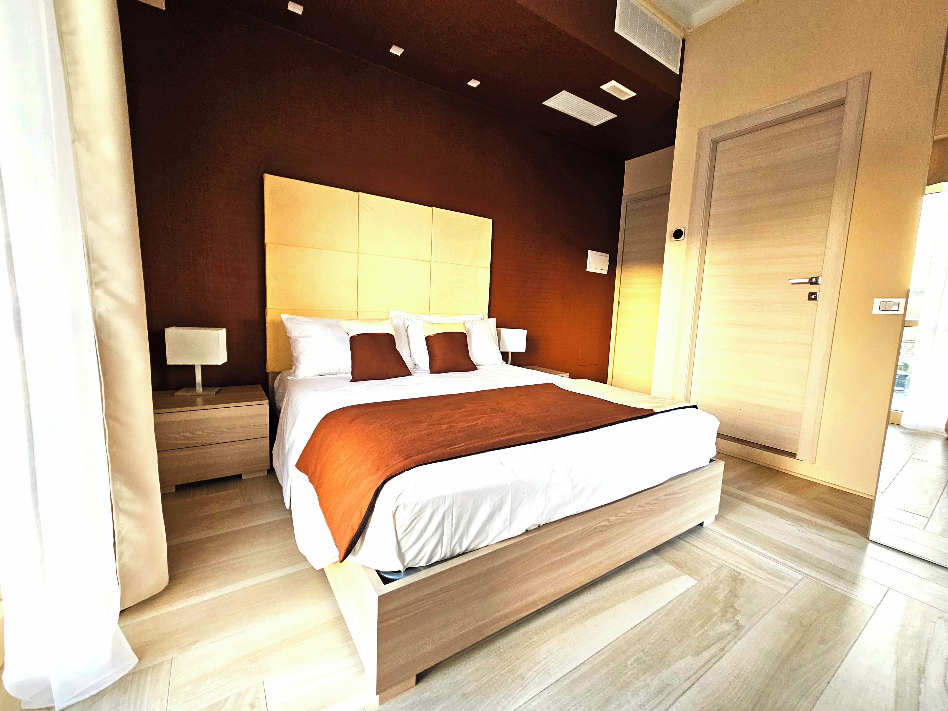 Una camera d'albergo moderna con un letto grande, una testiera in legno e un pavimento in legno.