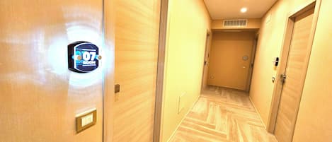 A hallway with wooden flooring and doors, including a sign for room 107.