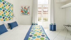 Una habitación de hotel con una cama, un ventanal con cortinas, un balcón y una pared con un diseño colorido.