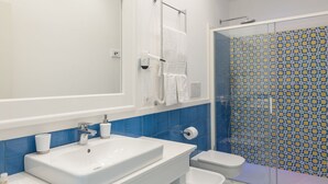 Un baño moderno con un espejo grande, lavamanos blanco y retrete.
