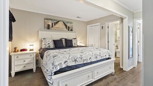 A bedroom with a bed, nightstand, and a painting on the wall.
