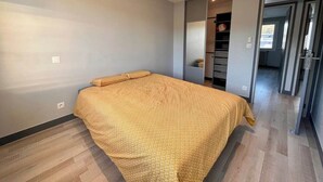 A bedroom with a bed, a wardrobe, and a door leading to another room. - Beautiful modern 7th floor apartment with panoramic views  (Chambéry)