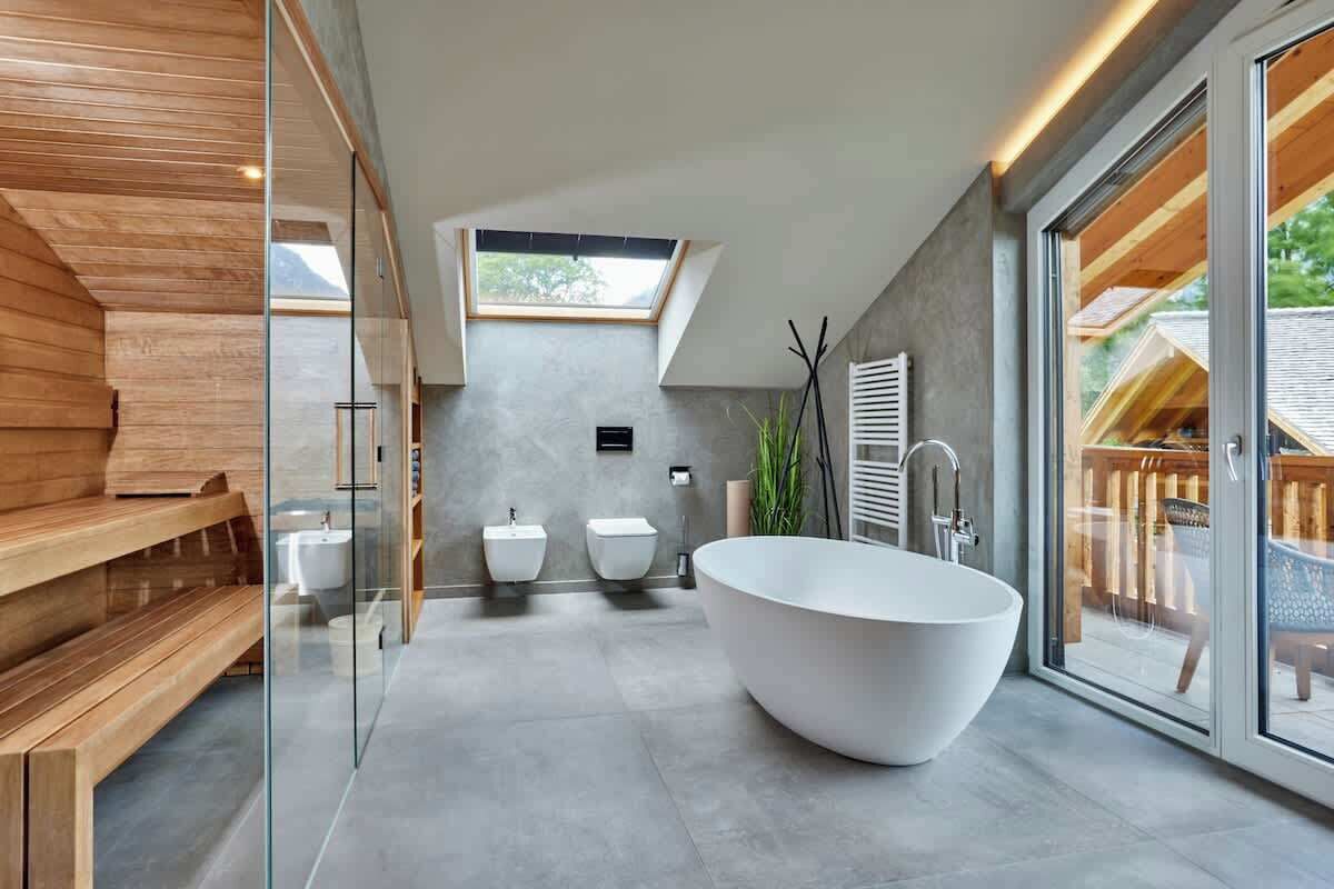 A modern bathroom with a freestanding bathtub, a wooden bench, and a skylight.