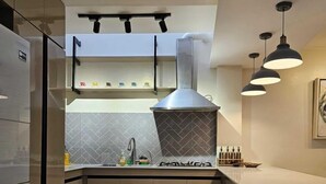 Una cucina moderna con piano cottura integrato, cappa aspirante e luci a sospensione.