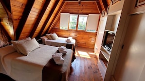 A cozy attic bedroom with a large bed, a smaller bed, and a table. - CasaAlpina (Tandil)