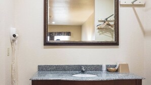A bathroom with a granite countertop sink, a mirror, and a towel rack. - Hiway Inn Express Of Coalgate (Coalgate)